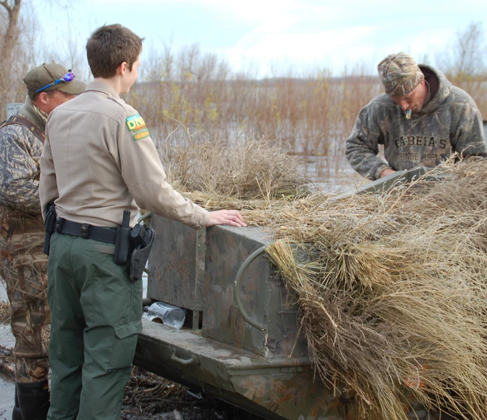 Conservation officer speaking with hunters in the field.