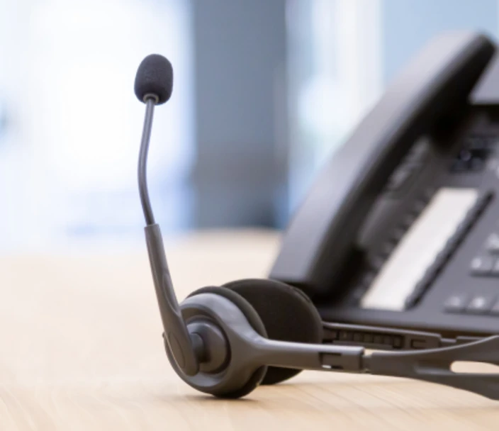 A phone attached to a headset, laying on a desk.