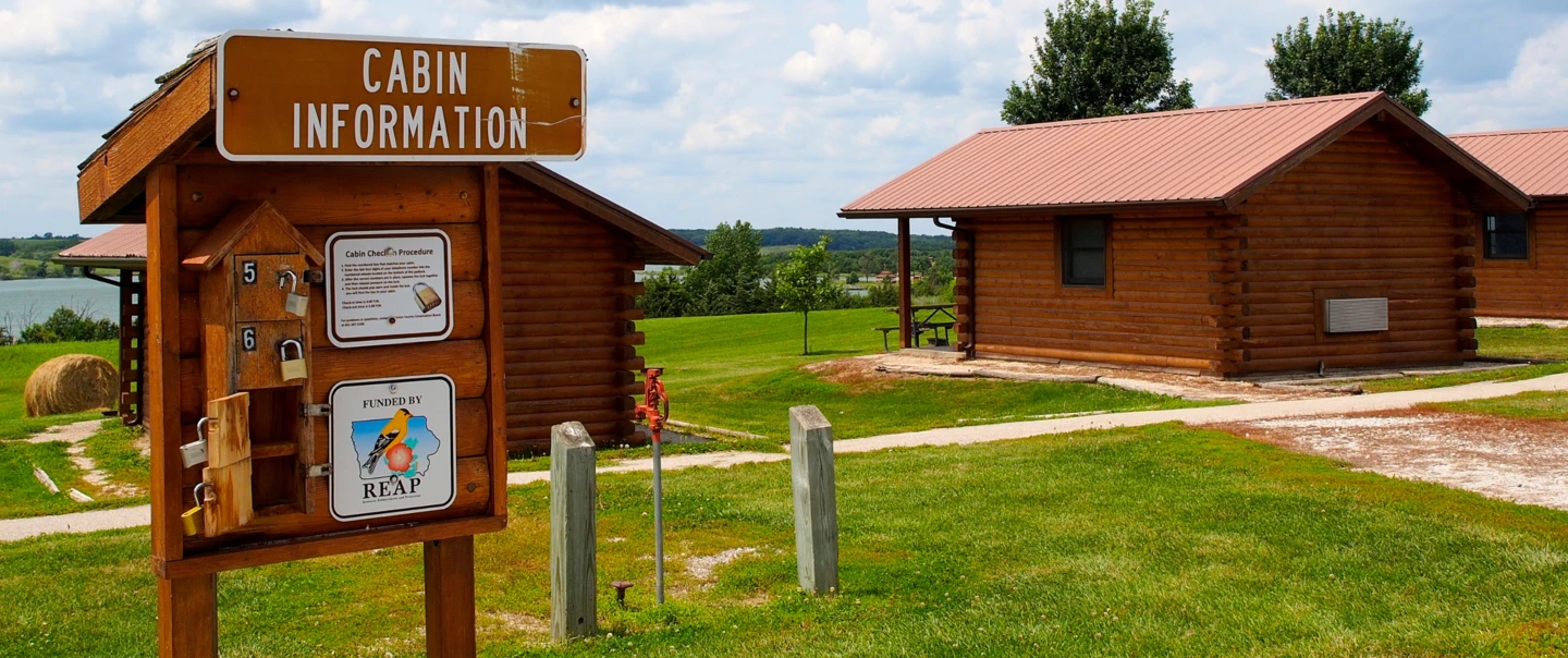 Three Mile cabin information sign with REAP funding sign posted.