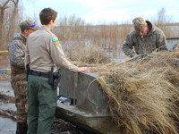 Conservation officer speaking with hunters in the field.